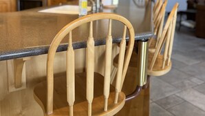Een keuken met houten kastjes, een granieten aanrechtblad en een keukeneiland in de vorm van een boom met barkrukken.