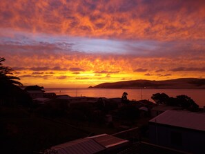 A sunset over a coastal town with houses and a body of water.