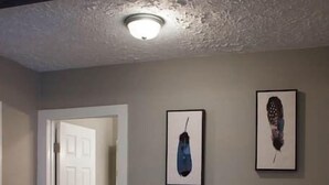 A bedroom with a bed, a nightstand, and two framed pictures on the wall.