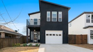 A modern two-story house with a black exterior, a white garage door, and a small balcony. - Overnight Gallery • The Art House • Near Downtown Dallas • Maduro Collection (Dallas)