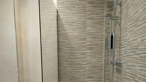 Ein modernes Badezimmer mit einer gläsernen Duschkabine, einer Toilette und einem Mülleimer.
