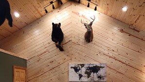Zona pranzo con pareti in legno e pavimento a spina di pesce, con una mappa del mondo appesa e un tavolo con sedie.