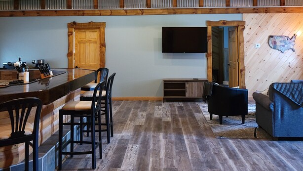 Un'ampia cucina con angolo bar, travi in legno a soffitto e un televisore piatto a parete.
