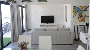 Un soggiorno moderno con un divano, una TV e lampade a sospensione.