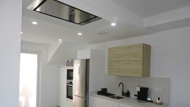 Una cucina moderna con forno integrato, frigorifero, lavello e macchina del caffè.