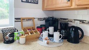 Keittiössä on kahvinurkkaus, johon kuuluu Keurig-kahvinkeitin, kuppeja ja kahvikapseleita.