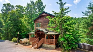 A two-story log cabin with a porch and a staircase leading to the upper level. - Luxury Cabin between Pigeon Forge and Gatlinburg (Sevierville)