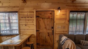 L’intérieur d’un chalet en bois, avec un coin bar, un canapé et un tapis à motifs.