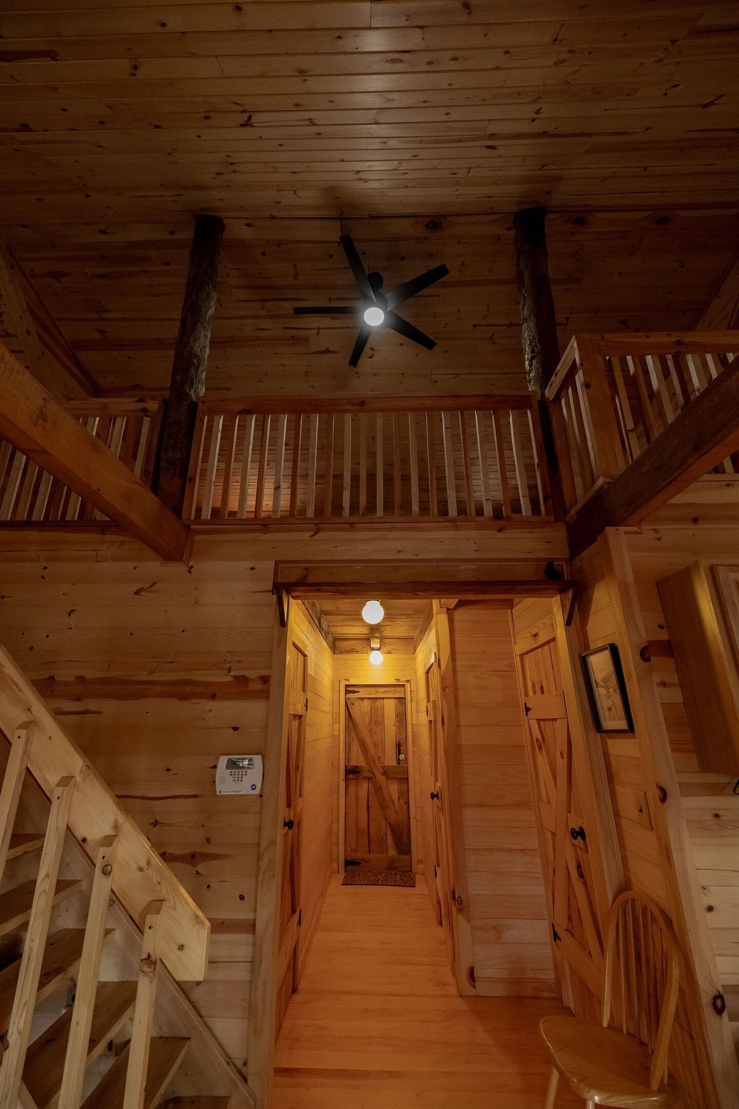 Un intérieur en bois avec un escalier, un ventilateur de plafond et un luminaire.