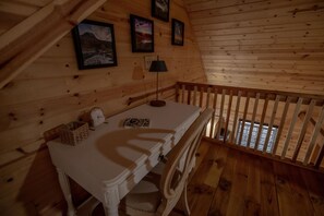 A wooden cabin interior with a white table, a lamp, and framed pictures on the wall. - Mountain Momma Hideaway (Upper Tract)