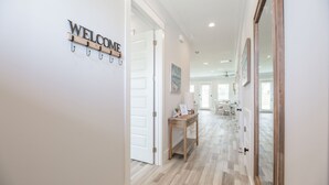 A hallway with a 'WELCOME' sign, a wooden table, and a view into a dining area. - 🌴Luxury 4BR Beach Home🏖GULF VIEW🌊4 min Walk To The Beach (Panama City Beach)