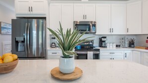 A modern kitchen with white cabinets, stainless steel appliances, and a wooden countertop with a potted plant. - 🌴Luxury 4BR Beach Home🏖GULF VIEW🌊4 min Walk To The Beach (Panama City Beach)