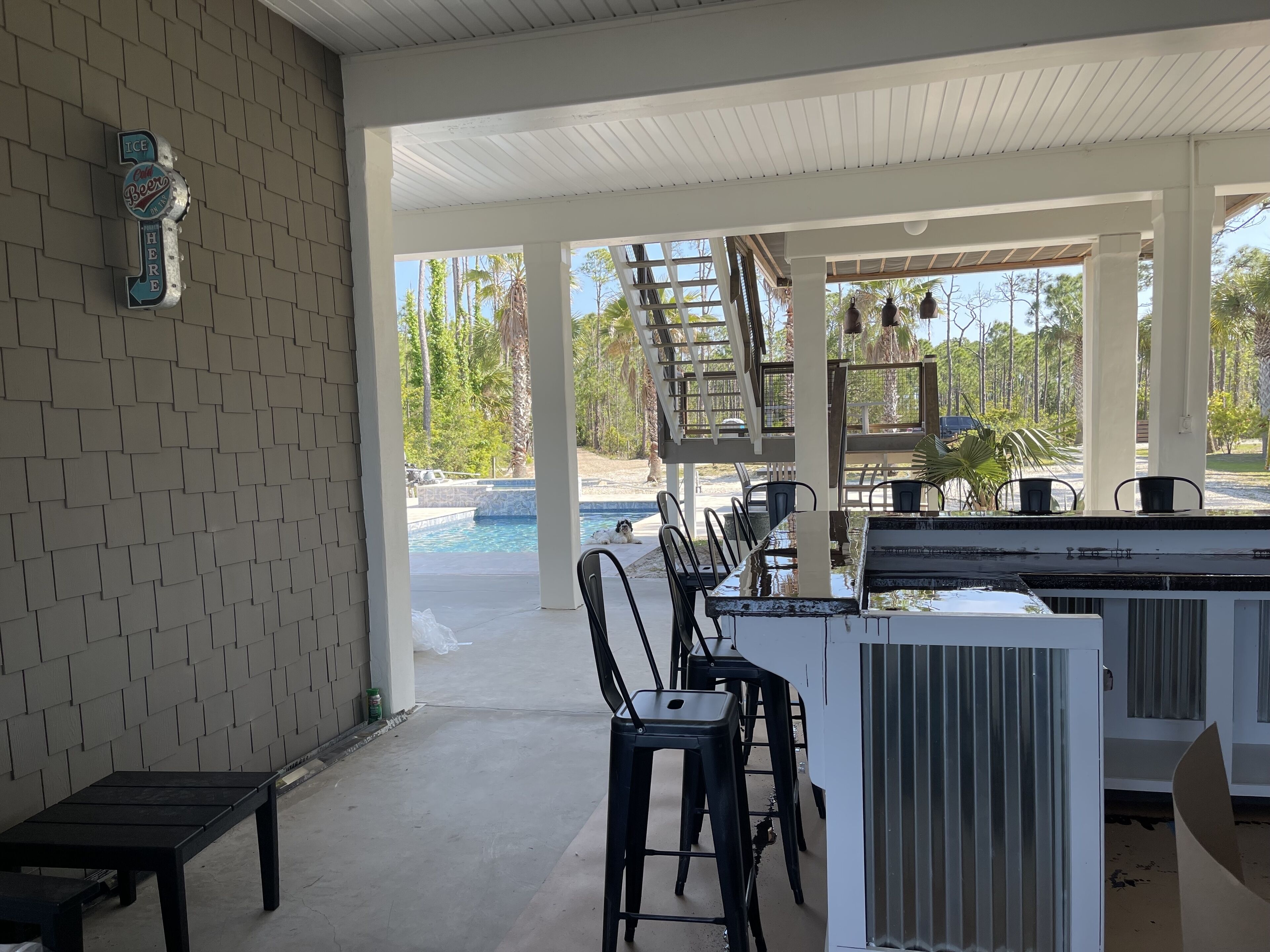 A covered outdoor area with a pool, bar, and seating.