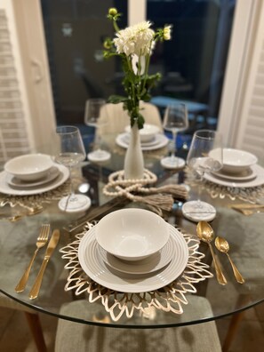 A dining table set with white plates, gold cutlery, and a vase with white flowers. - Charming 3B-2BA in Anaheim’s Heart (Anaheim)