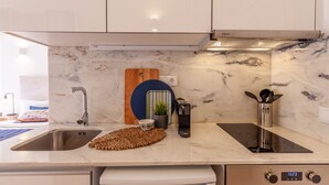 Una cocina moderna con un lavamanos de acero inoxidable, una estufa empotrada y un reloj digital que marca las 13:23.