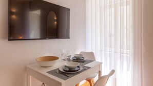 Un comedor con una mesa blanca, dos tazones, dos copas de vino y un cuenco de madera.