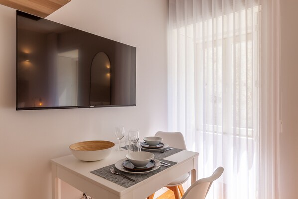 A dining area with a white table, two bowls, two wine glasses, and a wooden bowl.