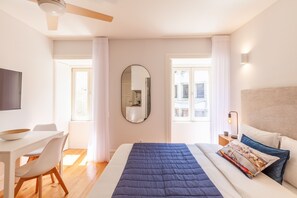 A modern hotel room with a large bed, a desk, and a chair.