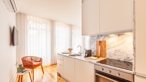 A modern kitchen with white cabinets, a marble countertop, and a built-in oven. - S. Bento Apart IV (G) (Oporto)