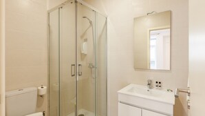 A modern bathroom with a glass-enclosed shower, a white sink, and a toilet. - D&S - Villa Apartments & Suites II (Oporto)