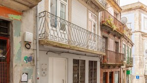 A historic building with a white door, a balcony with metal railings, and a cobblestone street. - D&S - Villa Apartments & Suites II (Oporto)