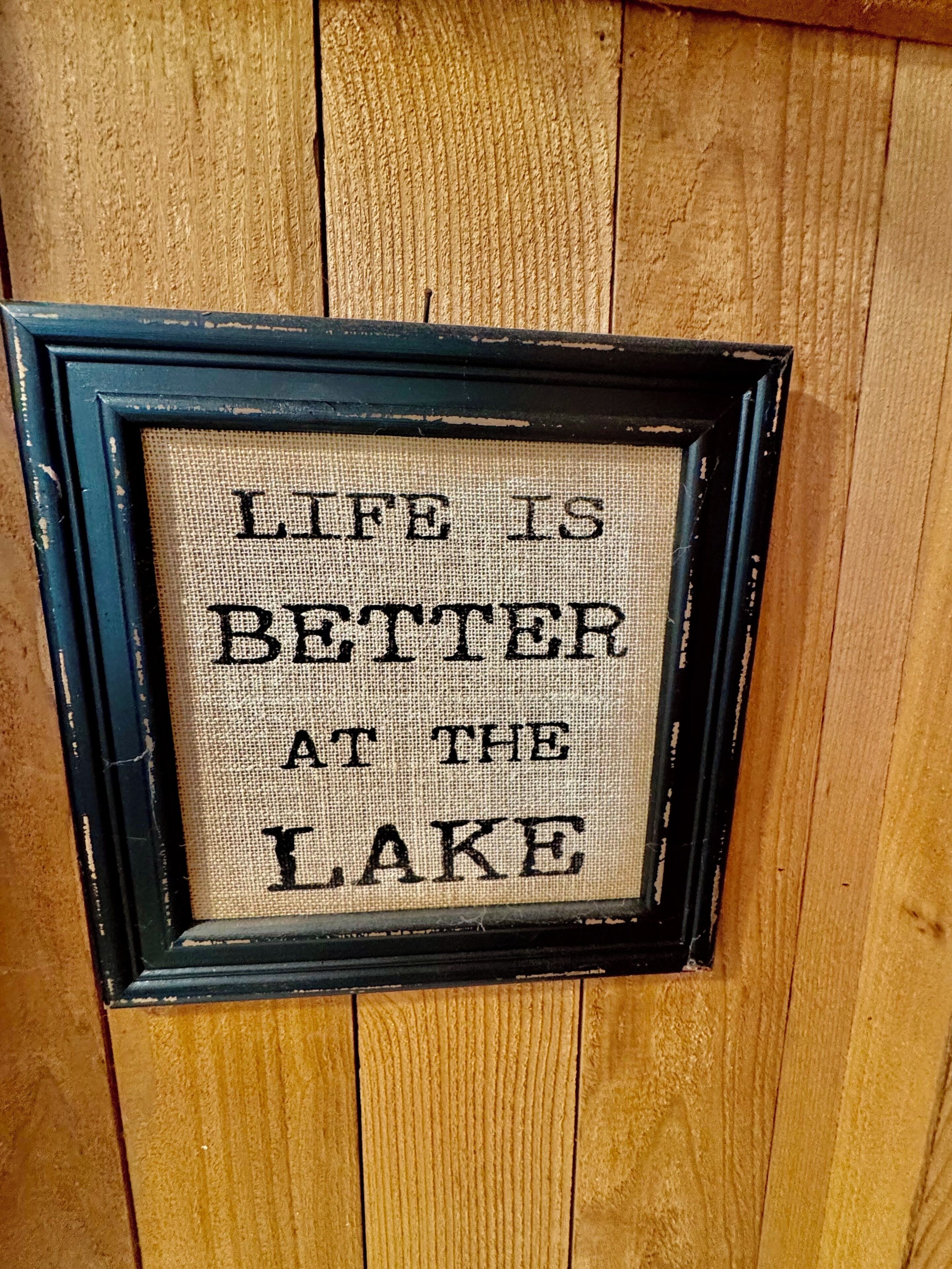 Un cartello incorniciato con la scritta 'Life is better at the lake'.
