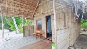 A bamboo structure with a wooden deck, a single chair, and a window with a red frame. - Guest House (West Papua)