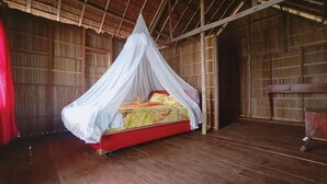 A single bed with a canopy in a room with wooden walls and floors. - Guest House (West Papua)