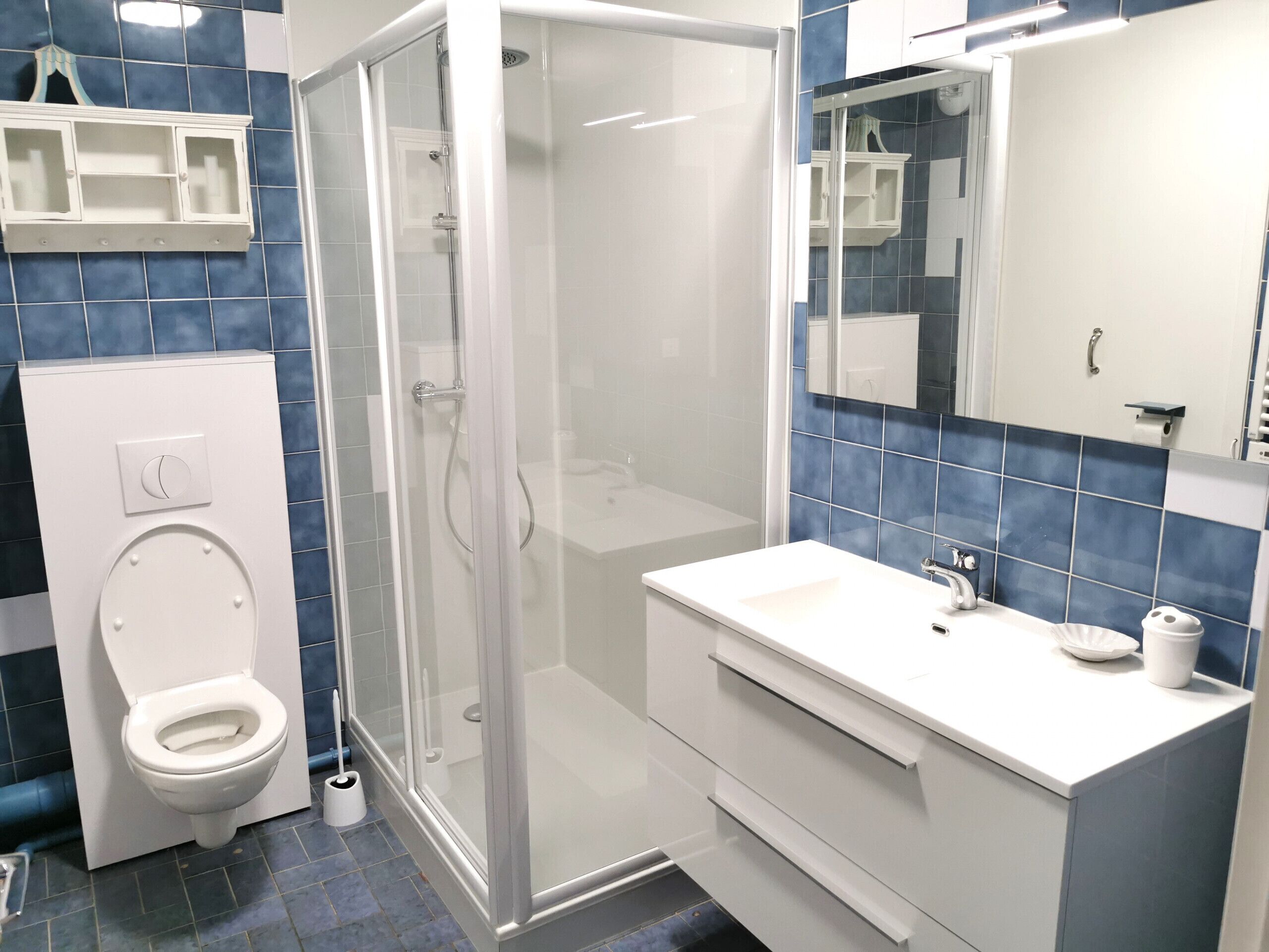 A modern bathroom with a glass-enclosed shower, a white sink, and a toilet.