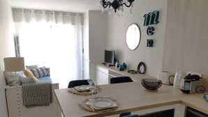 Una cocina moderna con una mesa de comedor para dos, un televisor y diversos electrodomésticos.