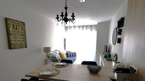 Una cocina moderna con una mesa de comedor para dos personas, una araña y una barra de desayuno.