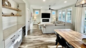 Une cuisine moderne avec des meubles blancs, un plan de travail en bois et un coin repas comprenant une table et des chaises en bois.