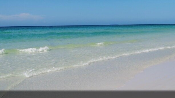 Een strand met helder turquoise water en wit zand.