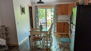 A spacious kitchen with wooden cabinets, a black refrigerator, and a dining area with a table and chairs.
