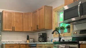 A kitchen with wooden cabinets, a stainless steel oven, a microwave, and a coffee maker.