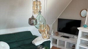 Un salon moderne avec un canapé vert, une table basse blanche et un téléviseur.