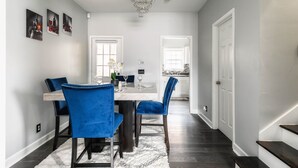 A modern dining area with a marble table, blue upholstered chairs, and a chandelier. - Central Charm: 5min to Broadway & DT, Free Coffee! (Nashville)