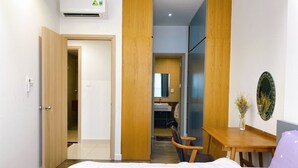 Ein Schlafzimmer mit Bett, Schreibtisch und Stuhl. Im Hintergrund ist ein Badezimmer zu sehen.
