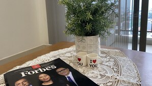 Ein Tisch mit einem Blumentopf, zwei Tassen und einer Ausgabe von Forbes.