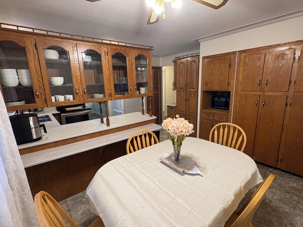 A kitchen with wooden cabinets, a dining table with chairs, and a coffee maker.
