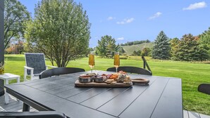Un espace de restauration en plein air avec une table dressée pour deux personnes, agrémentée d’une planche de charcuterie et de deux verres de vin.