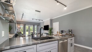 Une cuisine moderne dotée d’appareils électroménagers en acier inoxydable, de meubles blancs et d’un grand îlot central avec un évier.