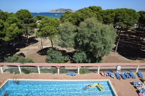 A swimming pool with lounge chairs and a view of the sea and trees. - Pineda Beach 25, L'Estartit - Center (Estartit (L´))