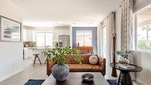 A modern living room with a sofa, a coffee table, and a vase with plants. - Beautiful 5 BR house with Olympic size Pool and SPA in Indio (Indio)