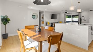 Cocina moderna con isla central, mesa de comedor de madera y sillas.
