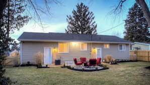 A single-story house with a front porch, a small patio with red chairs, and a well-maintained lawn. - Spacious, modern 4 bd, 2 bath w/upscale backyard (Columbus)