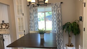 A modern kitchen with a dark countertop, white cabinetry, and a large window with patterned curtains. - Spacious, modern 4 bd, 2 bath w/upscale backyard (Columbus)