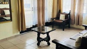 Una habitación con ventilador de techo, una mesa de vidrio, un banco de madera y una silla.