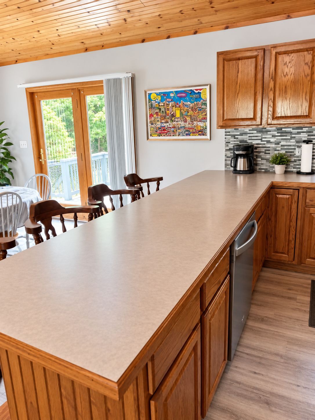 A kitchen with wooden cabinets, a large island, and a dining area with chairs.