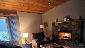 Una sala de estar con chimenea de piedra, un sofá, una mesa de centro y una lámpara.
